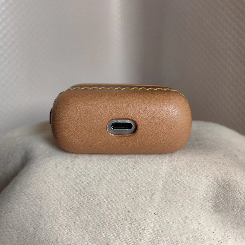 Bottom view of the Ronuo leather case for Bang & Olufsen Beo Grace earbuds, showing the precision-cut charging port access on the nude and coffee brown full-grain leather.