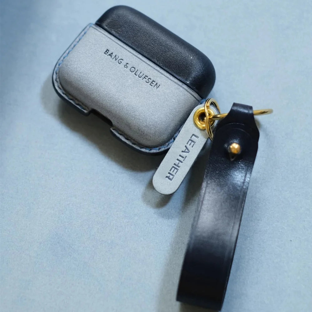 Navy blue and misty wax navy blue handcrafted leather earbuds case cover for Bang & Olufsen Beo Grace with leather wrist strap. The frosted wax-treated bottom leather displays a light grey surface finish and debossed logo.