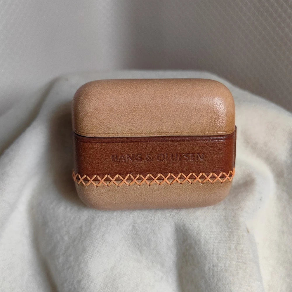 Close-up view of the handcrafted Ronuo leather cover for B&O Beo Grace, highlighting the contrast between the natural nude leather and the debossed Bang & Olufsen logo on the textured brown leather band.