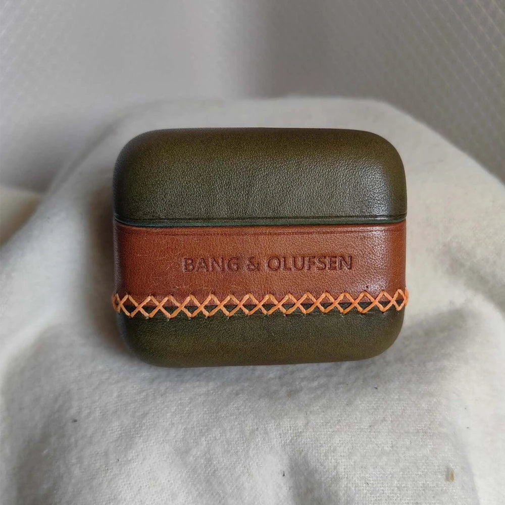 Artisan Olive Green leather earbuds cover for B&O Beo Grace with a contrasting brown central band, showcasing the natural grain and meticulous hand-sewn detailing.