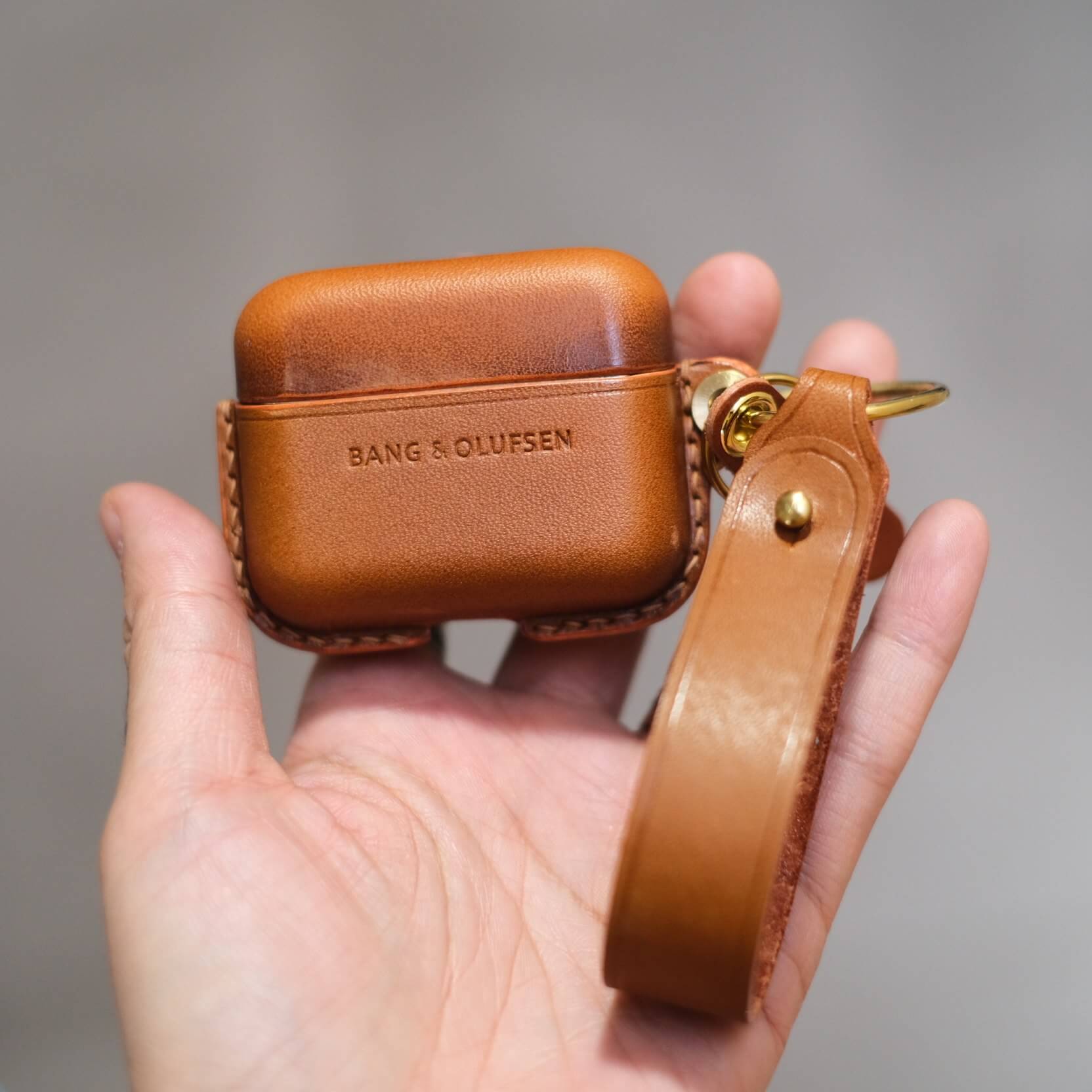 Étui pour écouteurs en cuir marron personnalisé et fabriqué à la main pour Bang & Olufsen Beo Grace, avec porte-clés latéral et lanière en cuir orange.