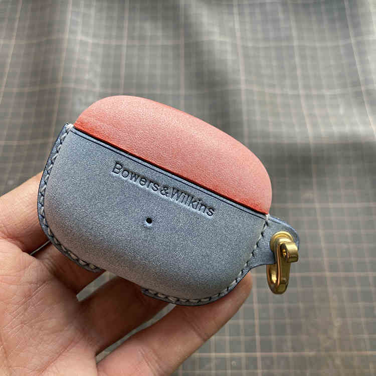 Echtes Lederetui für Bowers & Wilkins Pi8 Pi6 - Nahaufnahme einer Hand, die die Etuis Misty Wax Red (oben) und Misty Wax Blue (unten) mit Metallschließe hält.