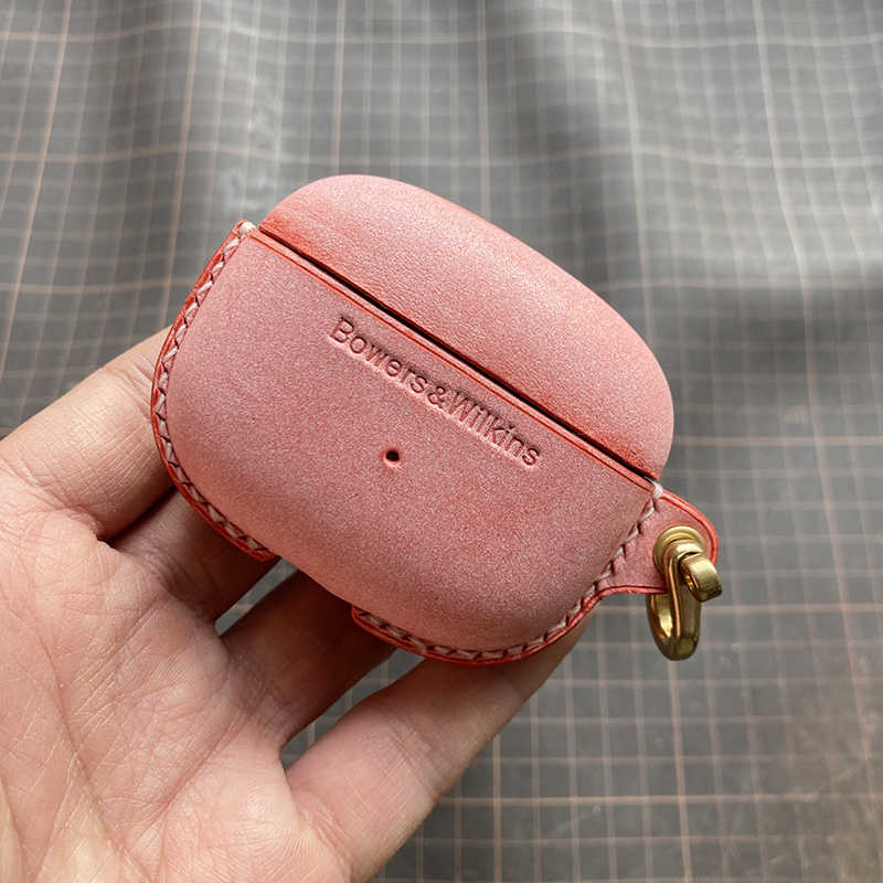 Schutzhülle aus echtem Leder für Bowers & Wilkins Pi8 Pi6 - Nahaufnahme einer Hand, die ein wächsernes rotes Etui mit Metallverschluss hält.