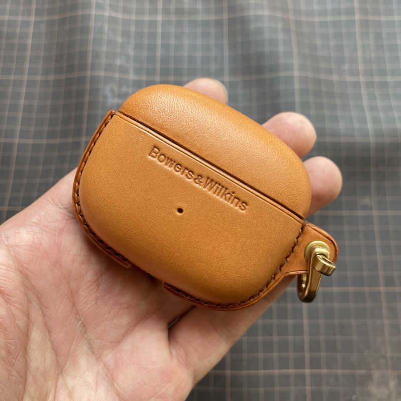 Echtes Lederetui für Bowers & Wilkins Pi8 Pi6 bluetooth earbuds - Nahaufnahme einer Hand, die ein gelb-braunes Etui mit Metallschließe hält