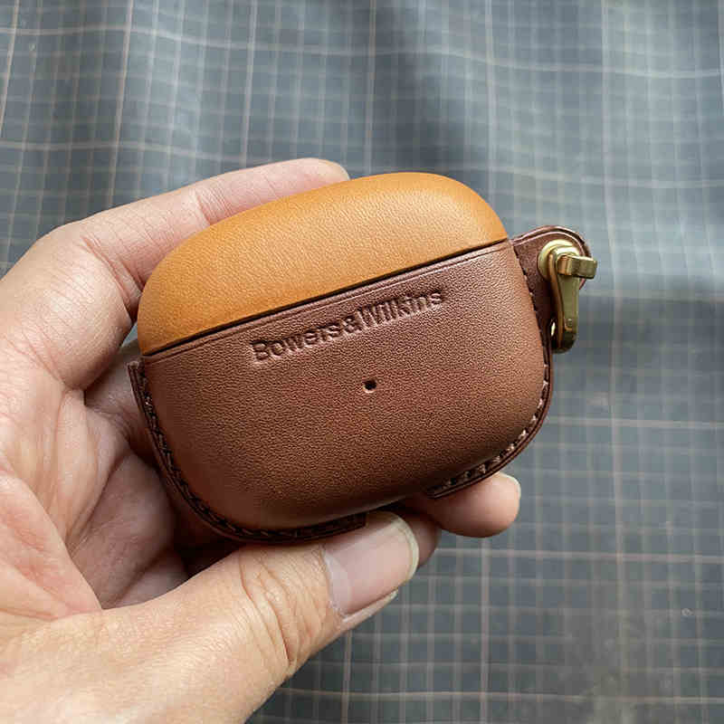 Schutzhülle aus echtem Leder für Bowers & Wilkins Pi8 Pi6 - Nahaufnahme einer Hand, die eine gelbbraune (oben) und eine kaffeefarbene (unten) Hülle mit Metallverschluss hält.