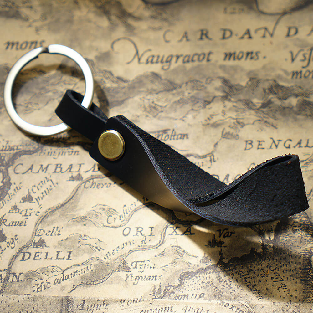 Handgefertigter Schlüsselanhänger aus Vollnarbenleder mit massivem Messingring in Schwarz für Autoschlüssel und Ohrhörer-Etui – Nahaufnahme des verzerrten Riemens