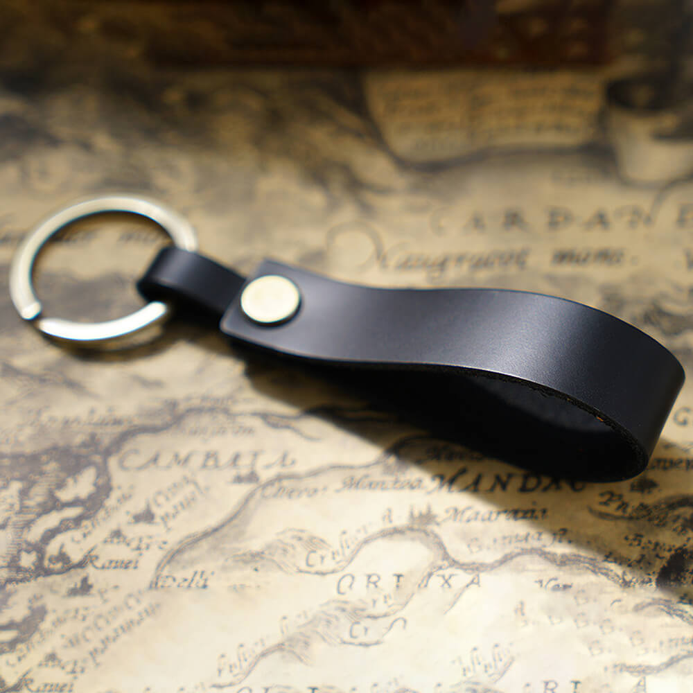 Handgefertigter Schlüsselanhänger aus Vollnarbenleder mit massivem Messingring in Schwarz für Autoschlüssel und Ohrhörer-Etui – Nahaufnahme des Materials