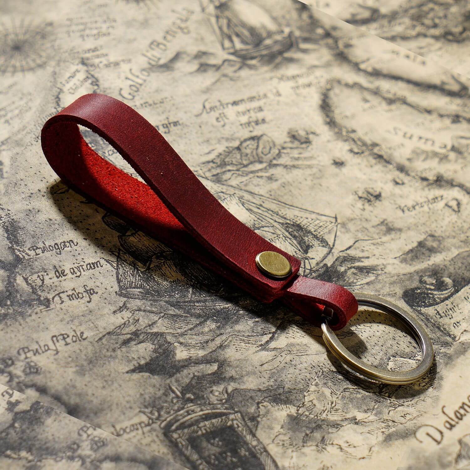 Handgefertigter Schlüsselanhänger aus Vollnarbenleder mit Metallring für Autoschlüssel und Ohrhörer-Etui in Rot, Nahaufnahme