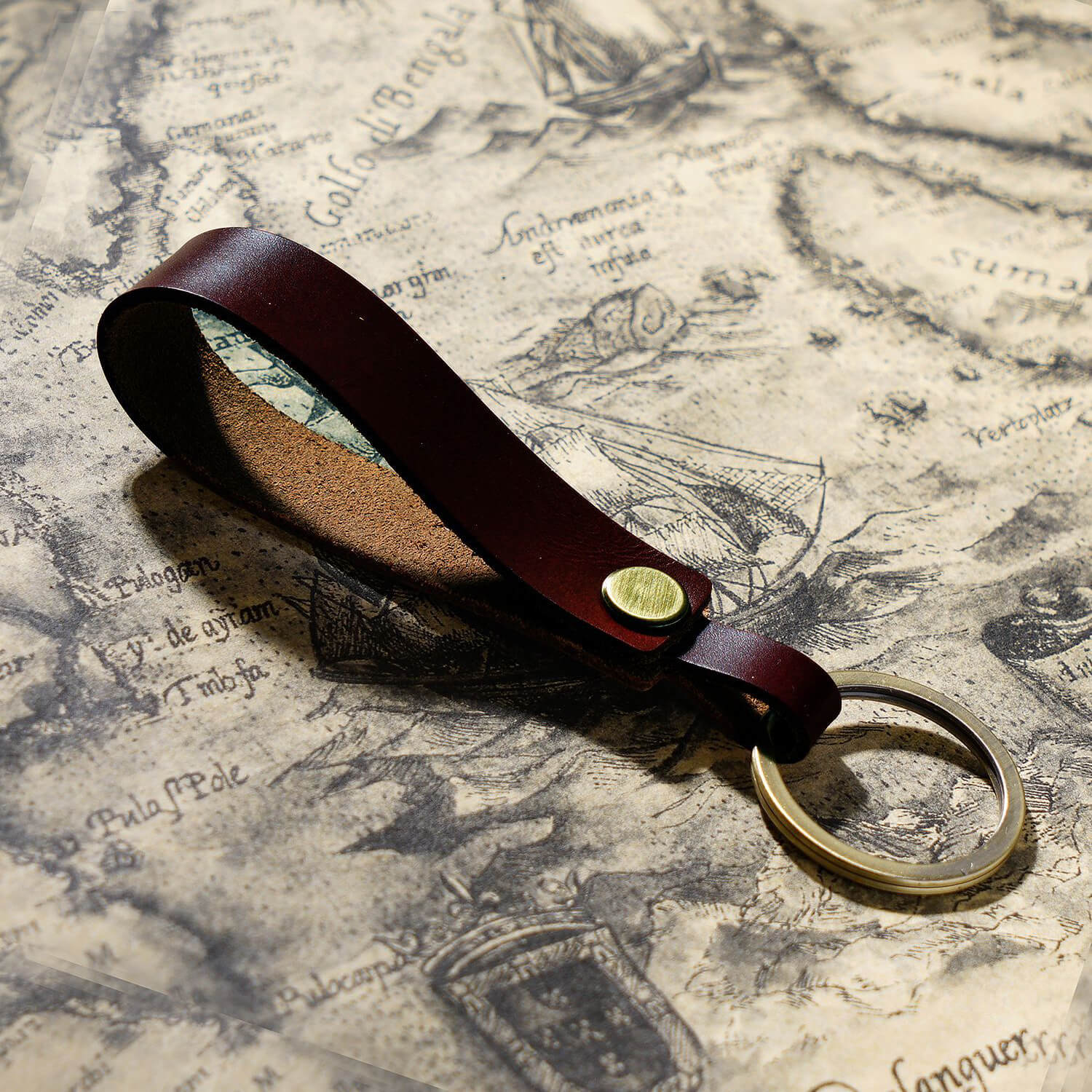 Handgefertigter Schlüsselanhänger aus Vollnarbenleder mit Metallring für Autoschlüssel und Ohrhörer-Etui in dunkelrotbraun, Nahaufnahme