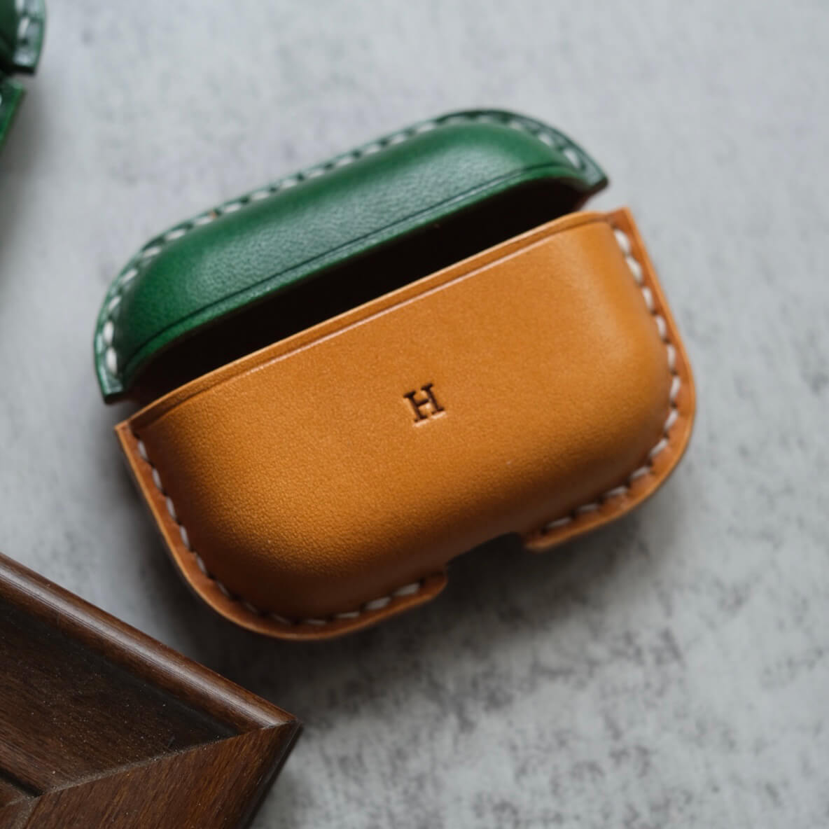Two-tone handcrafted leather earbuds case for AirPods Pro 3 in green and yellow brown with custom engraving "H" personalized design options , showing premium stitching