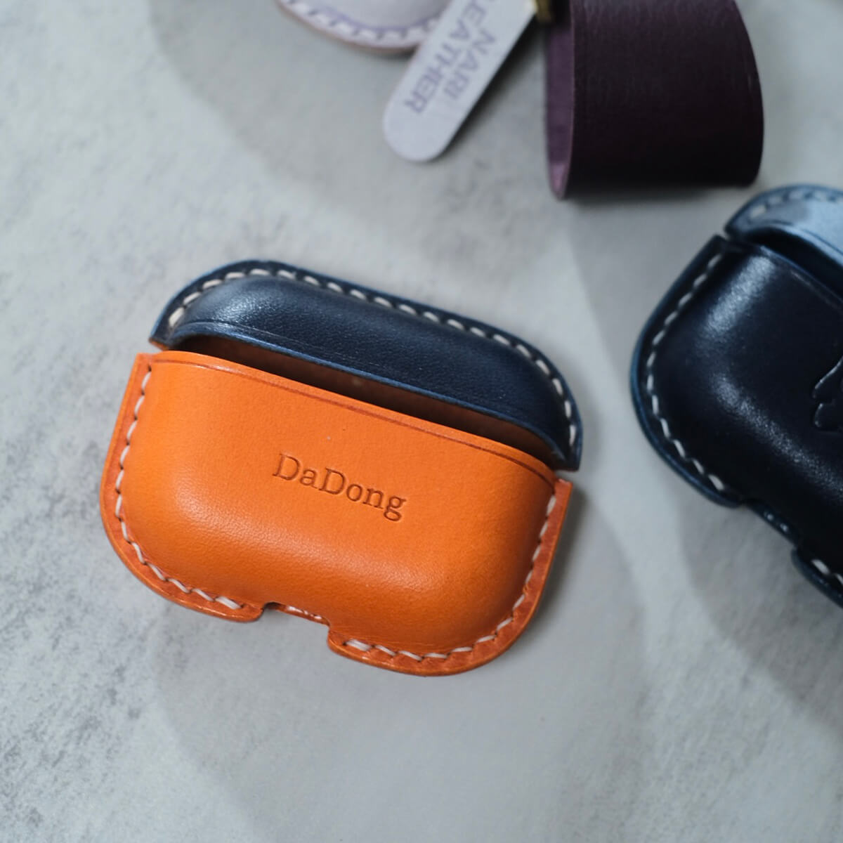 Navy and orange two tones handcrafted personalized leather earbuds case for AirPods Pro 3 with customized engraving text "DaDong" design example.