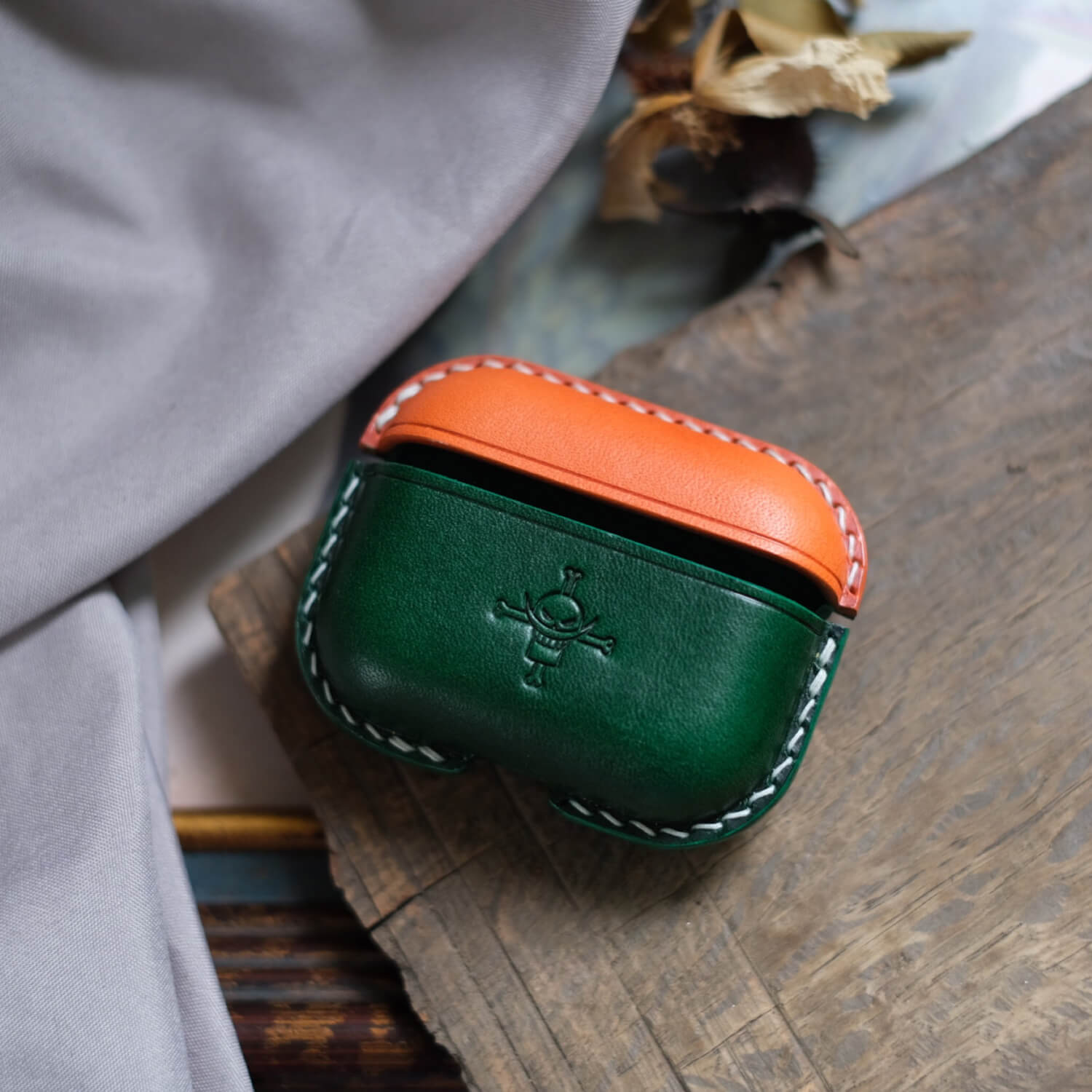 Orange and green handcrafted leather earbuds case for AirPods Pro 3 with custom engraved personalized pattern design.