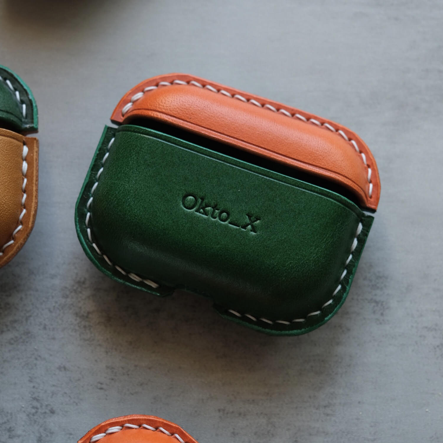 Orange and green handcrafted leather earbuds case for AirPods Pro 3 with custom engraved text "Okto_X" personalized design options , showing premium stitching