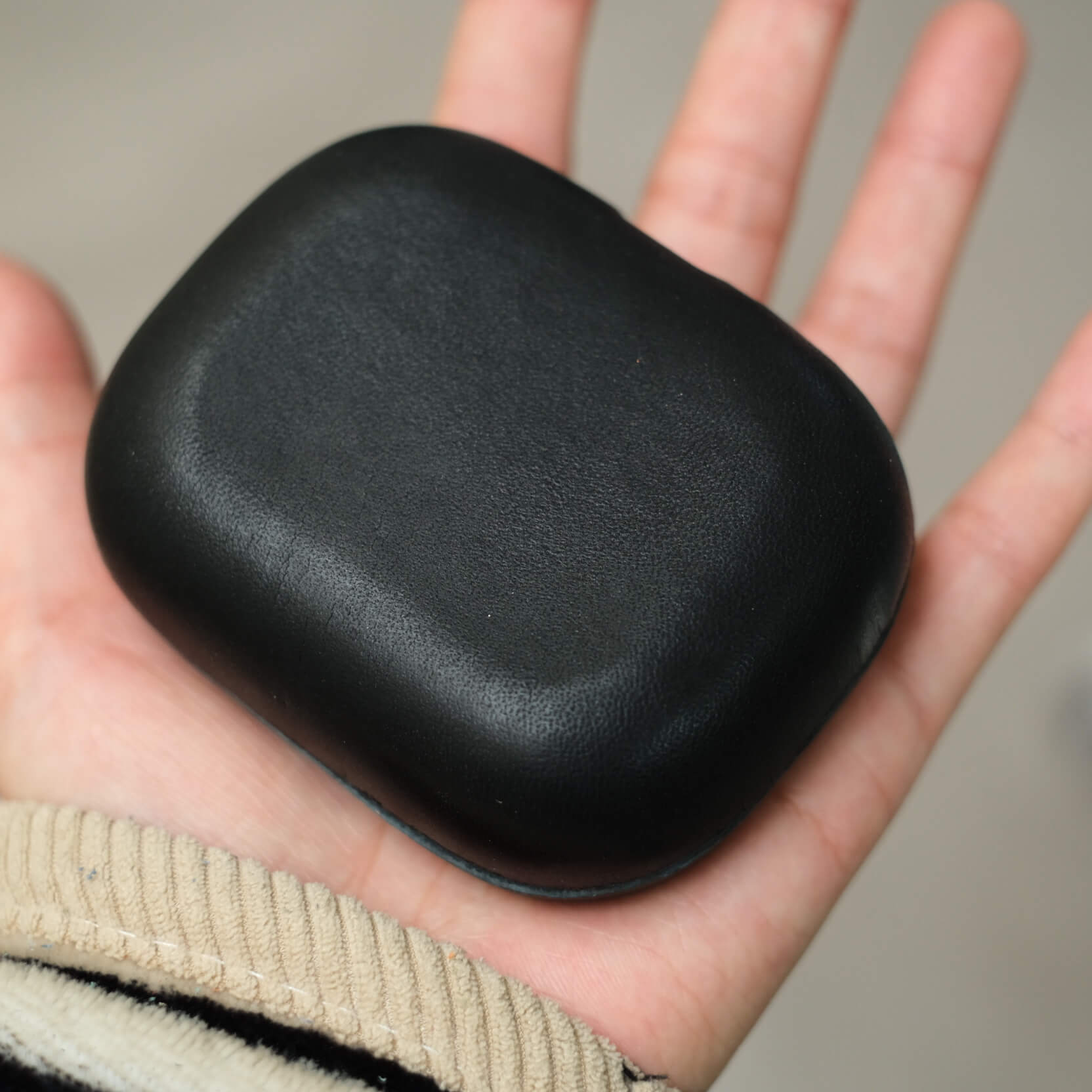 hand-holding handcrafted black genuine leather Beyerdynamic Amiron 200 earbuds case&#39;s bottom close-up conveying a sleek and modern design