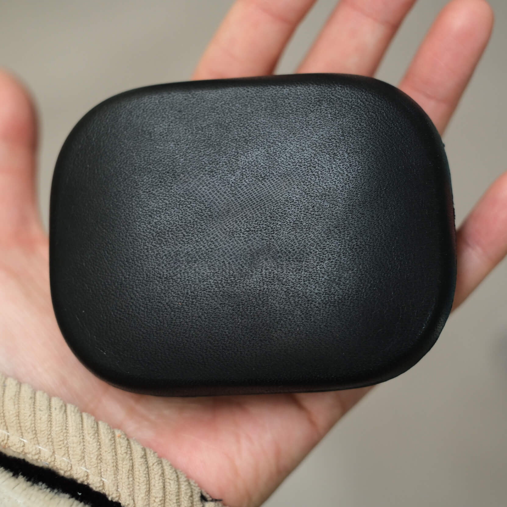 Close-up hand-holding handcrafted black genuine leather earbuds case with debossed Beyerdynamic logo conveying a sleek and modern design