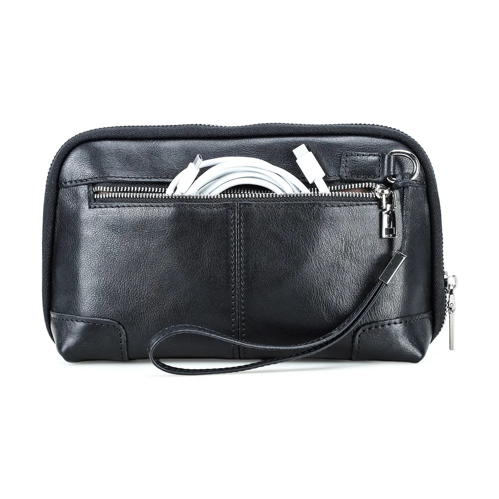 Front view of a handmade black vegetable-tanned leather clutch bag with a white charging cable tucked into the back zippered pocket.