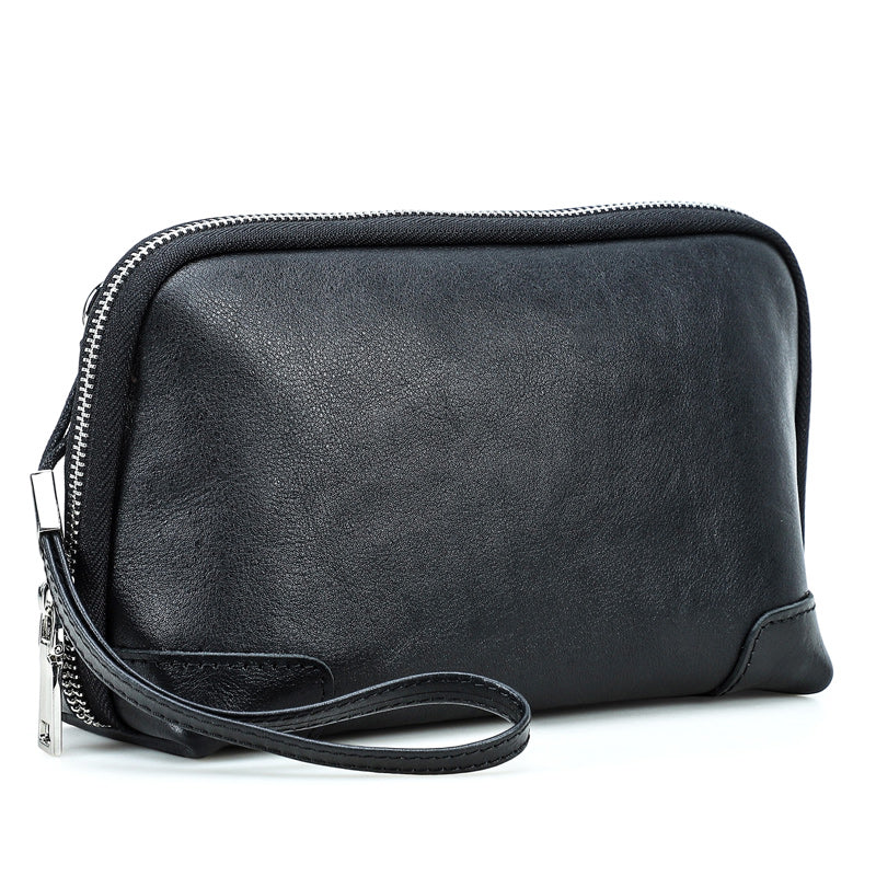 Handmade black vegetable-tanned leather clutch bag with zipper closure, wristlet strap, and vintage textured finish.