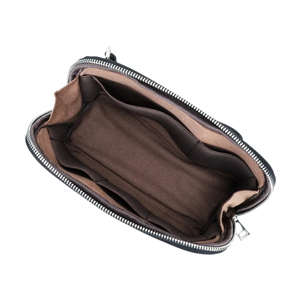 Top-down open view of a handmade black vegetable-tanned leather clutch bag, showing the dark brown lined interior, multiple organizing compartments, and smooth silver zipper.