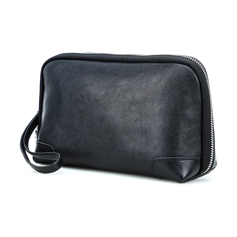 Front view of a handmade black vegetable-tanned leather clutch bag with zipper closure and wristlet strap