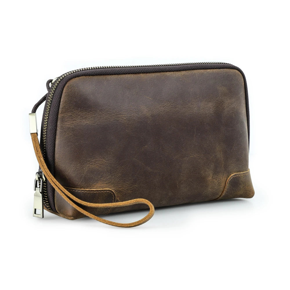 Front view of a handmade coffee brown vegetable-tanned leather clutch bag with zipper closure, wristlet strap, and vintage textured finish.